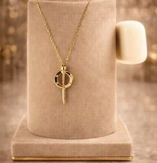 Gold necklace with a pendant on a beige stand against a blurred background