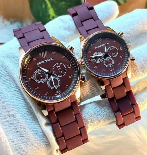 Two Emporio Armani watches with purple and rose gold straps on a light fabric background.